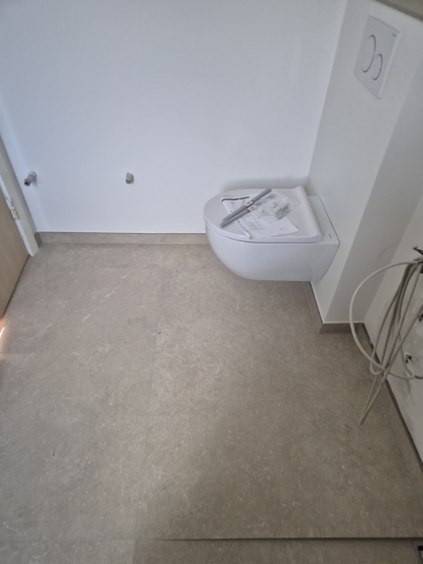Væghængt toilet på flisebelagt badeværelse